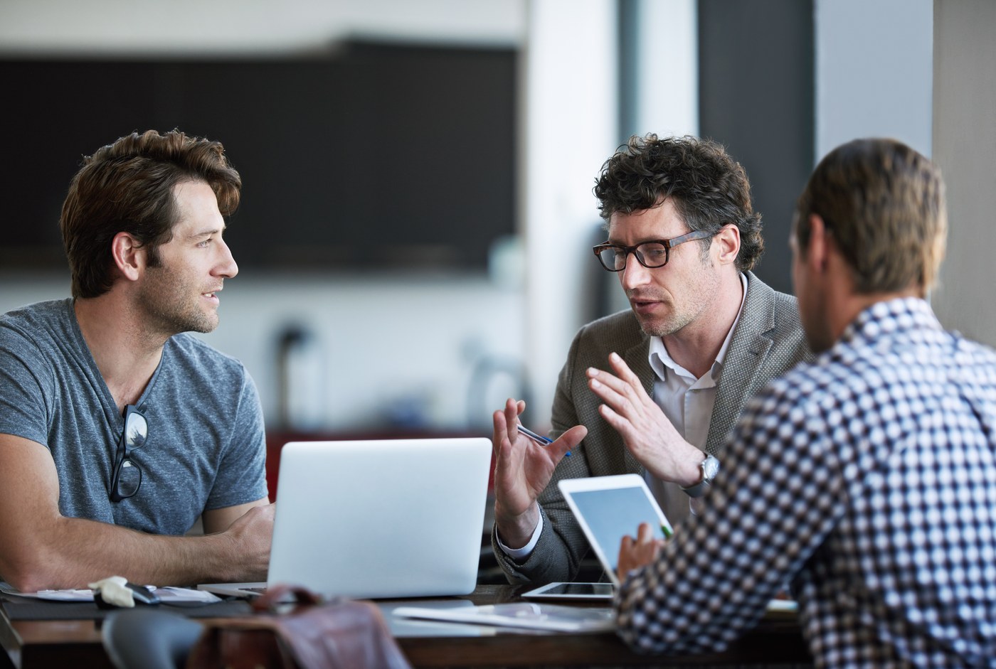 Three businesspeople discussing ideas around a laptop